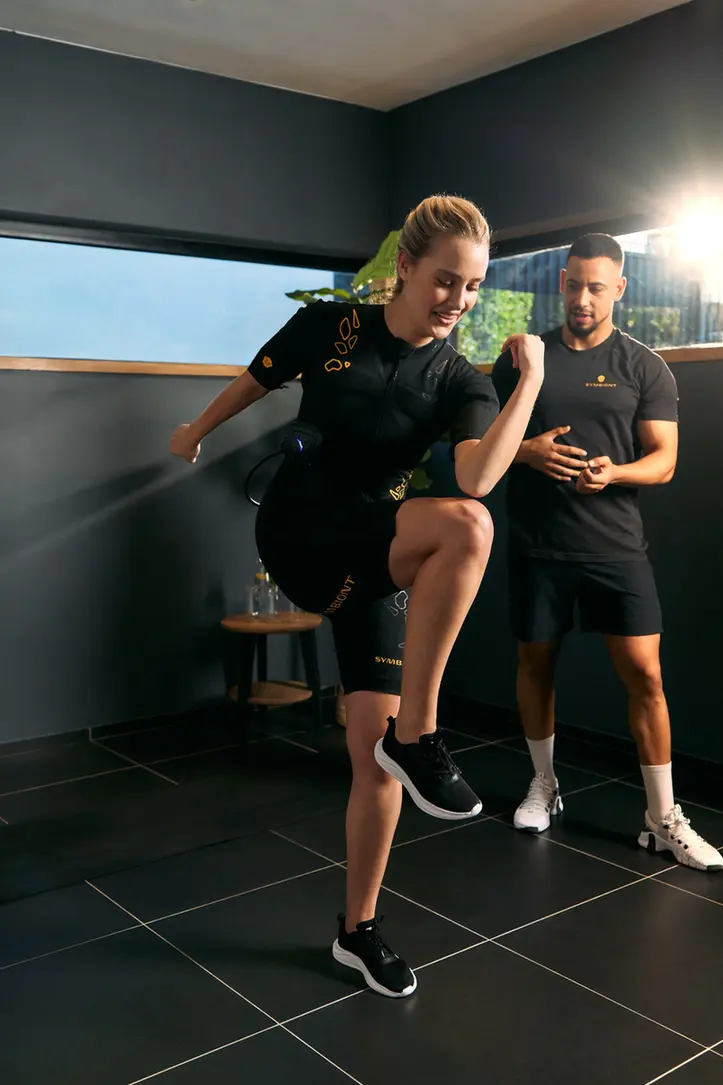 Erlebe SYMBIONT EMS-Training in deinem lokalen EMS-Studio Ein Personal Trainer betreut einen Kunden im SYMBIONT EMS-Anzug während einer Probesitzung in einem lokalen EMS-Studio. Erlebe personalisiertes Training, individuelle Betreuung und Motivation in deinem EMS-Probetraining.
